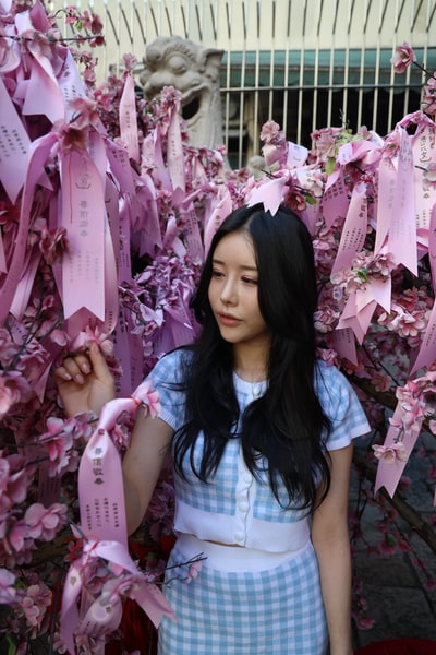 Dressed in white and blue plaid shirt woman standing beside the pink flowers
